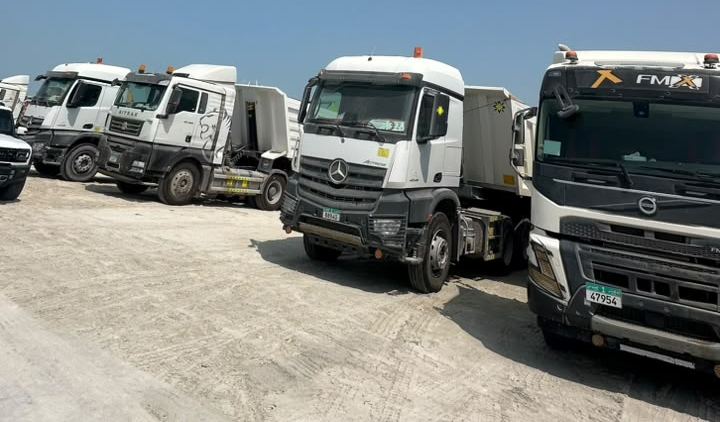 Company trucks lined up on a sandy yard