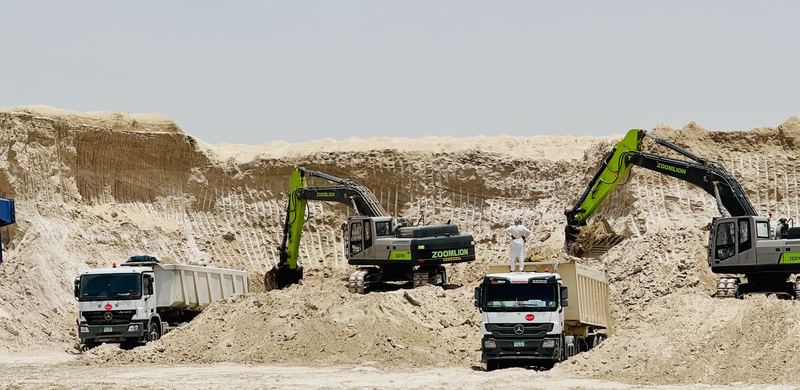 Two company excavators loading tipper trucks at a borrow pit