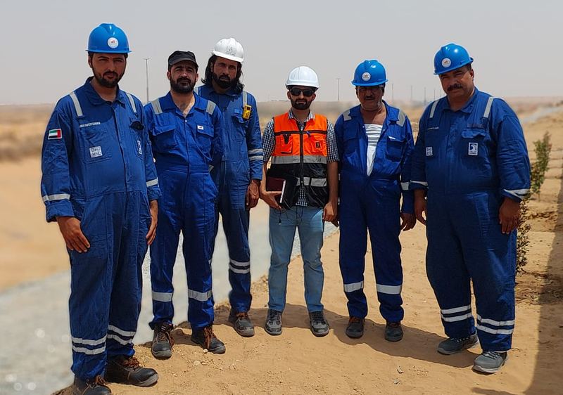 Company staff in coveralls and helmets at a project site
