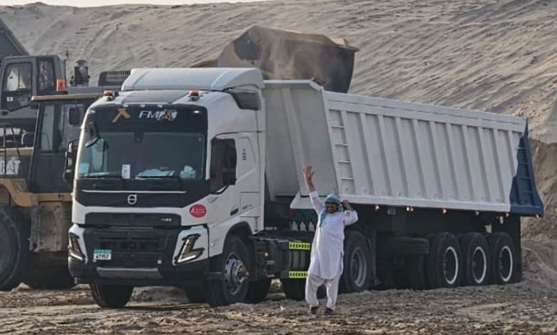 Wheel loader filling a tipper trailer pulled by a white truck