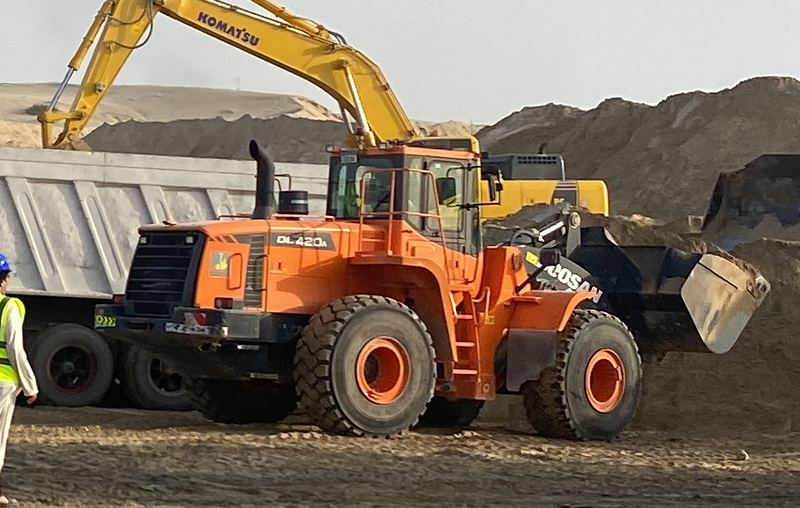 Orange wheel loader carrying material on site